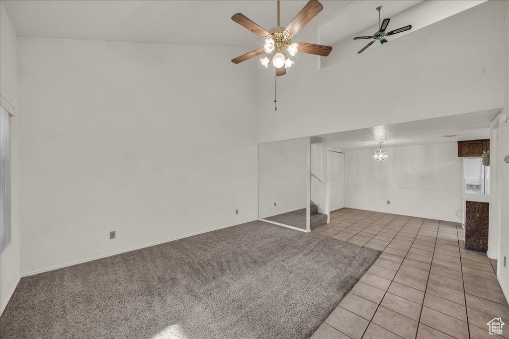 Below grade area with a ceiling fan, light tile patterned flooring, a chandelier, and stairway