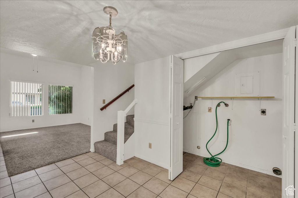 Interior space featuring a chandelier, tile patterned floors, a textured ceiling, and carpet floors
