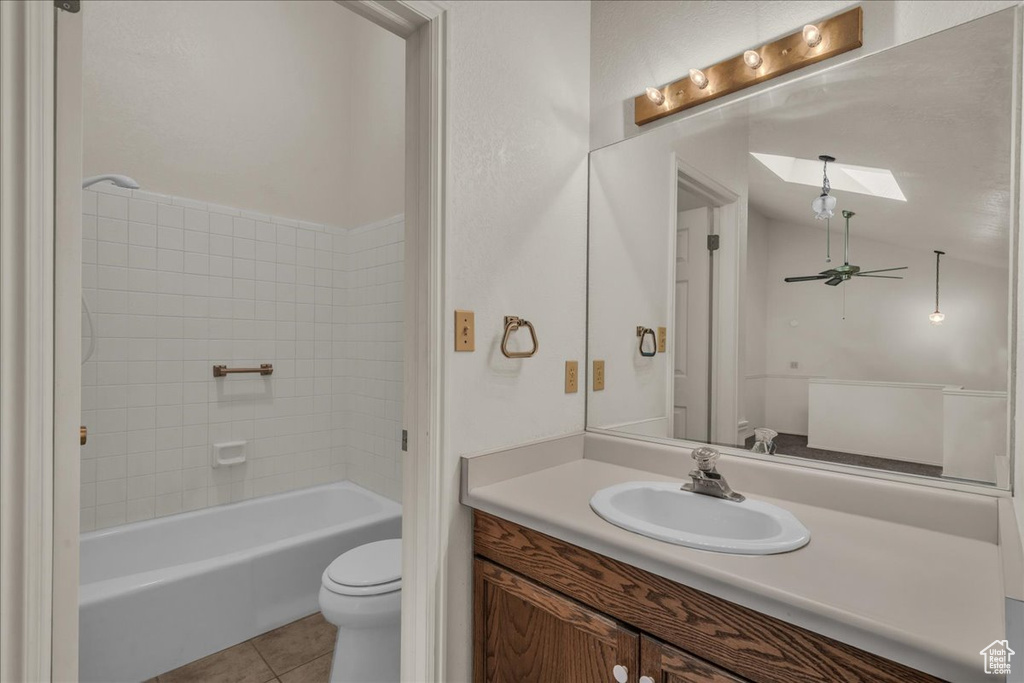 Full bath featuring a skylight, toilet, tile patterned floors, and vanity