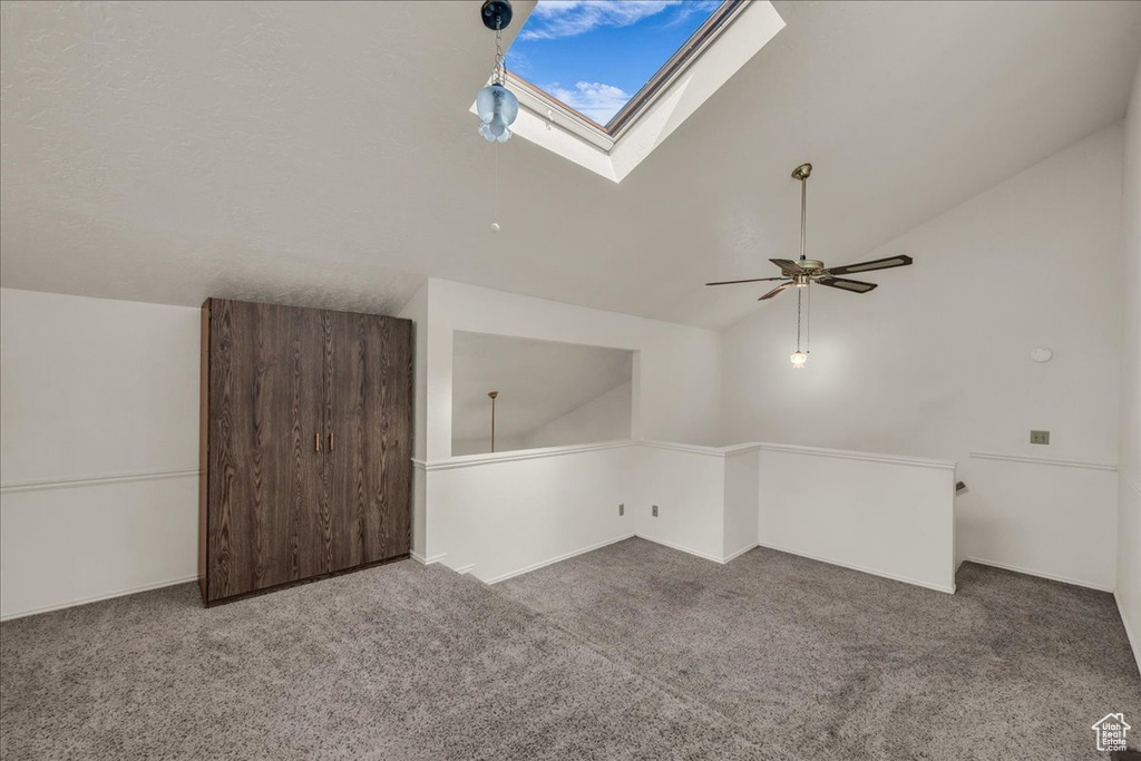 Additional living space featuring lofted ceiling, carpet floors, a skylight, and a ceiling fan