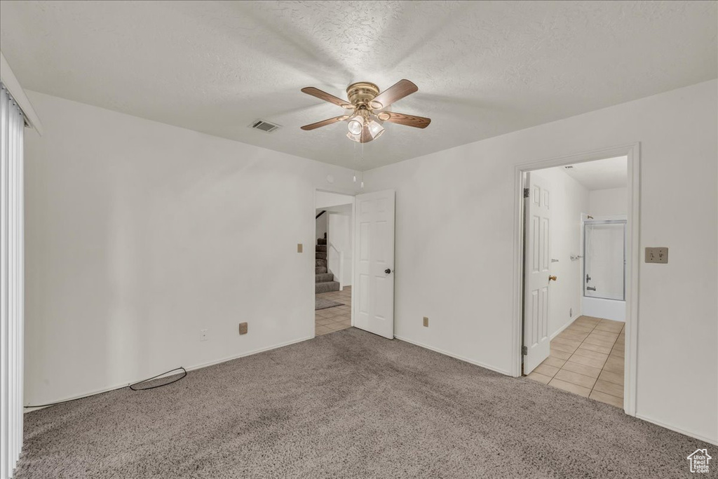 Unfurnished bedroom with carpet flooring, a textured ceiling, tile patterned flooring, baseboards, and a ceiling fan