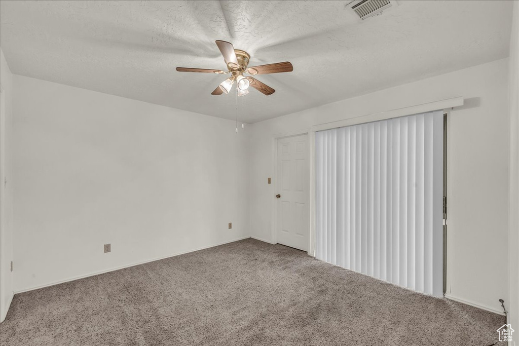 Carpeted empty room with ceiling fan, a textured ceiling, and baseboards