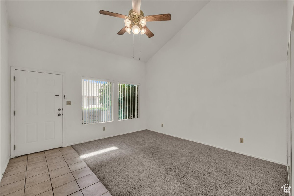 Foyer with ceiling fan, high vaulted ceiling, light carpet, light tile patterned floors, and baseboards
