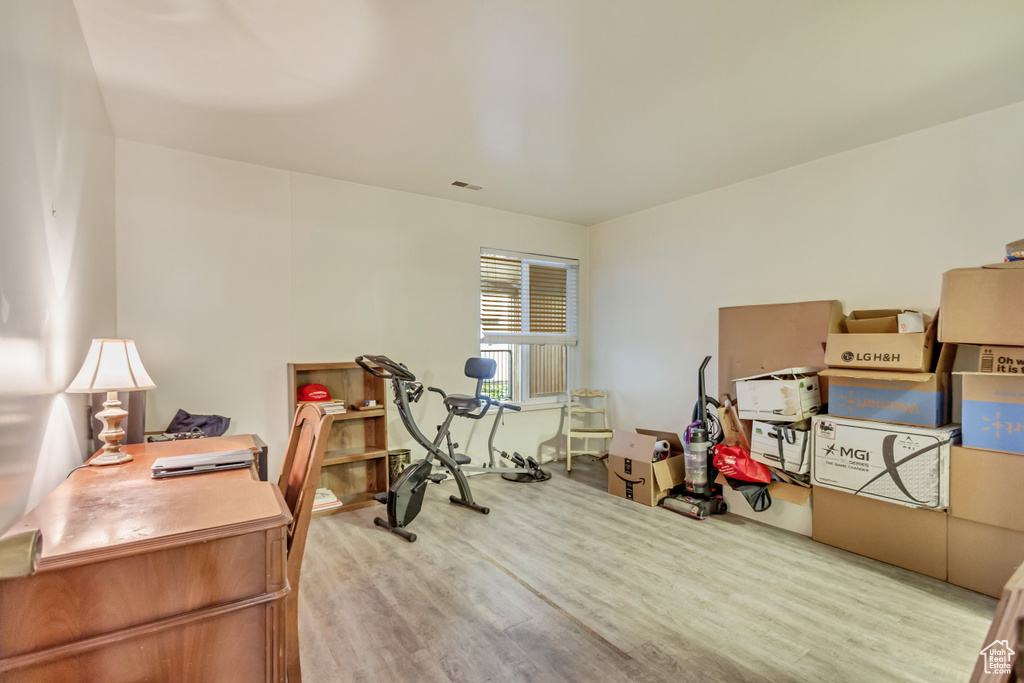 Home office with light wood-type flooring and visible vents