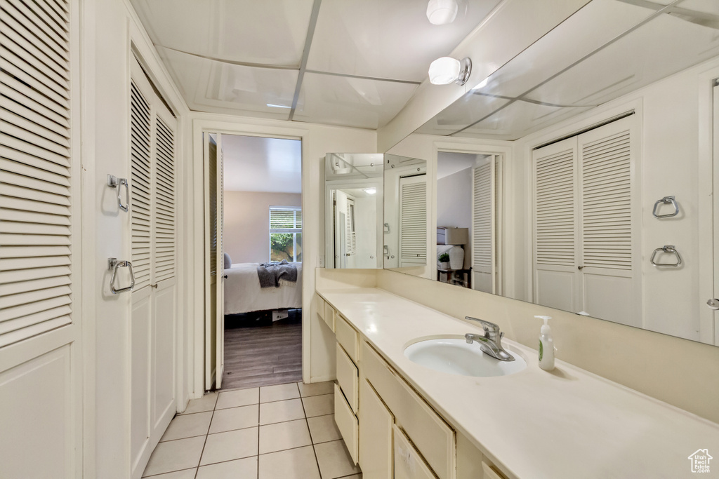 Ensuite bathroom featuring tile patterned flooring, a closet, vanity, and ensuite bath