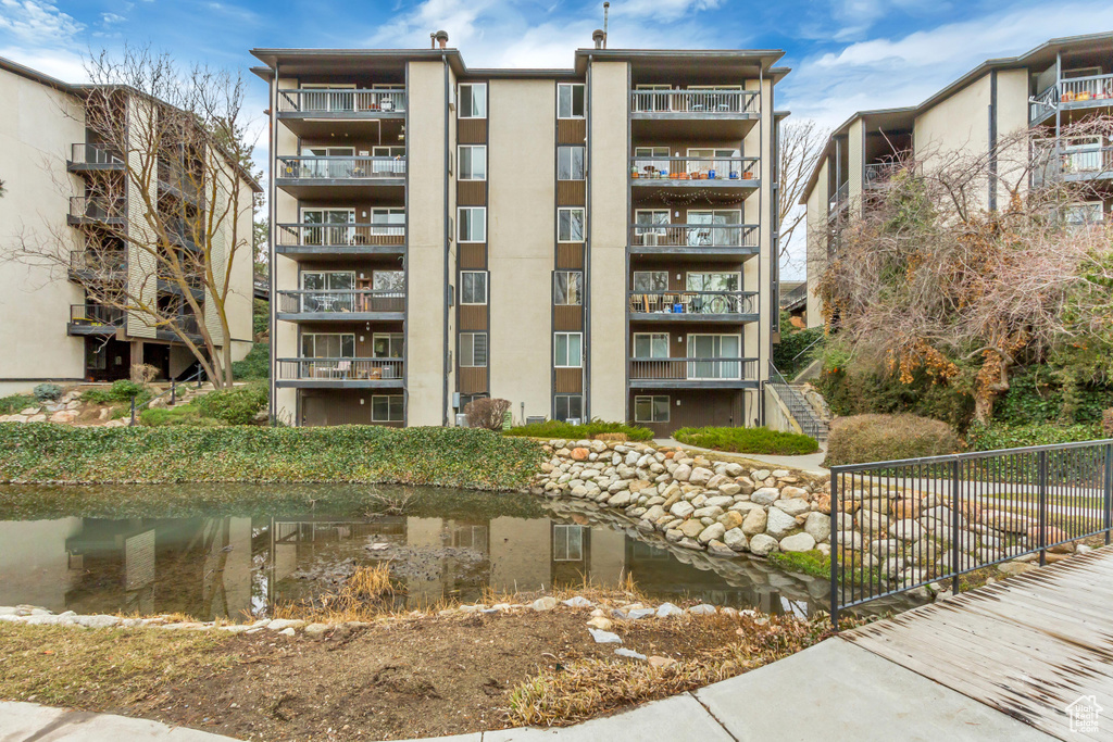 View of property with a water view, fence, and stairway