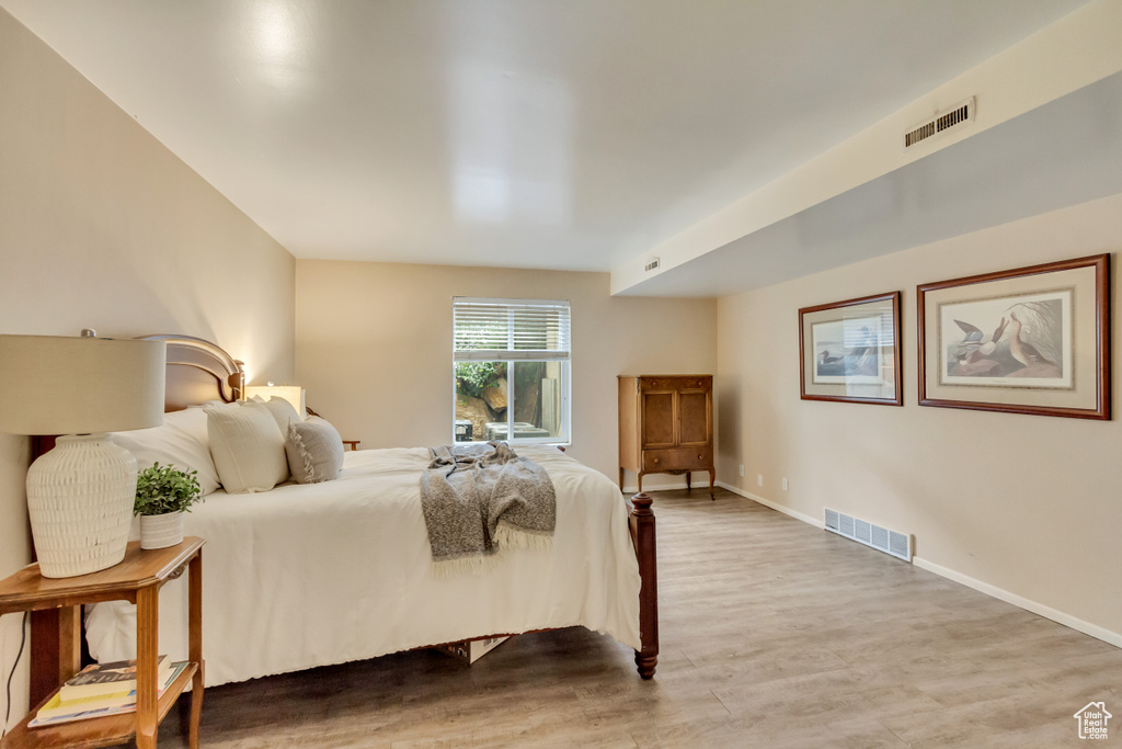 Bedroom with baseboards, visible vents, and wood finished floors