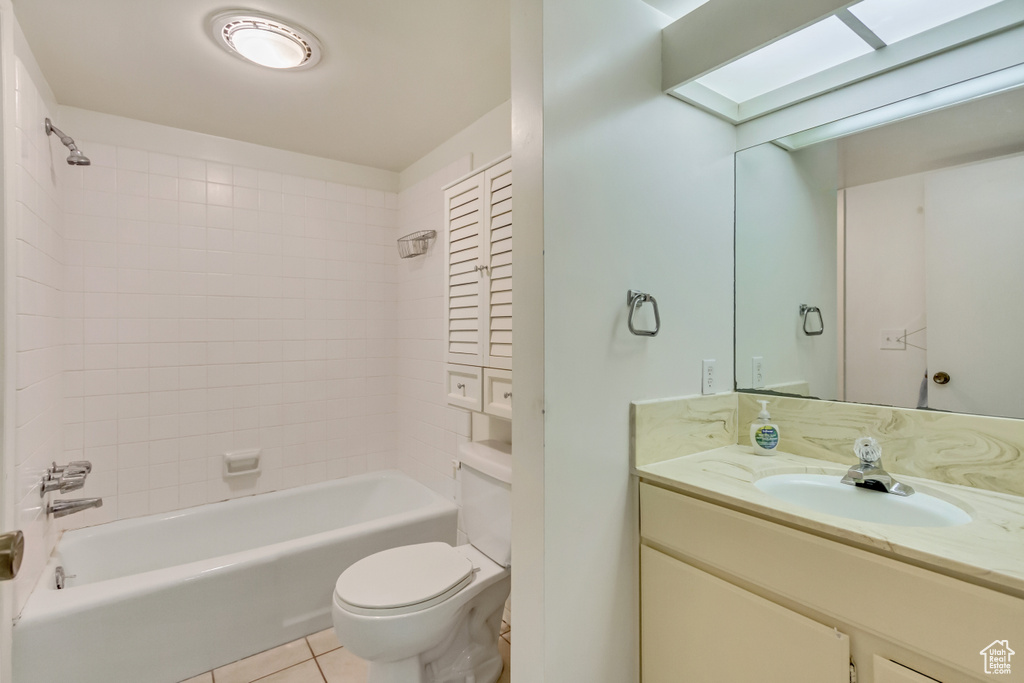Full bathroom with a skylight, toilet, tile patterned flooring, vanity, and shower / washtub combination