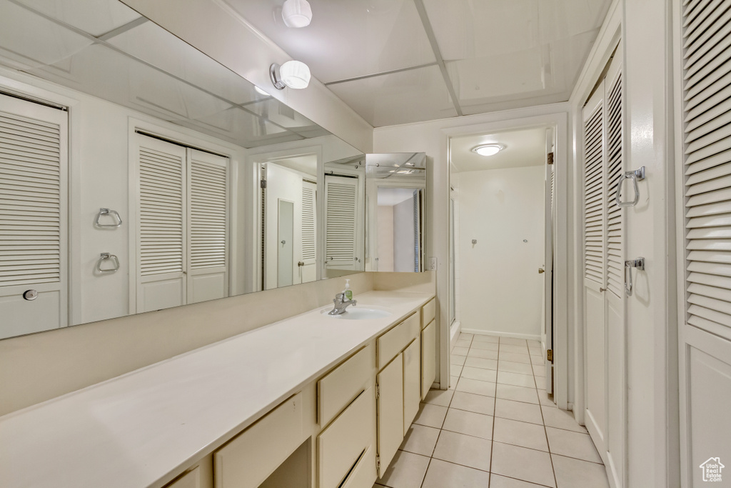 Bathroom featuring a paneled ceiling, a closet, vanity, and tile patterned floors