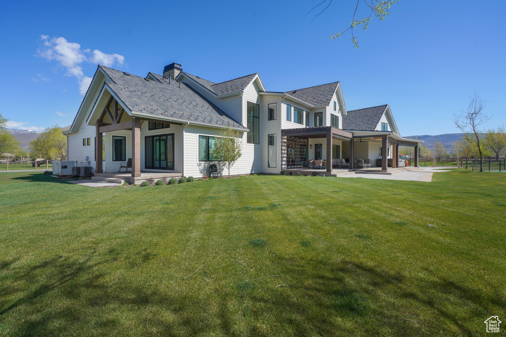 Rear view of property with a yard, a patio area, a mountain view, and fence