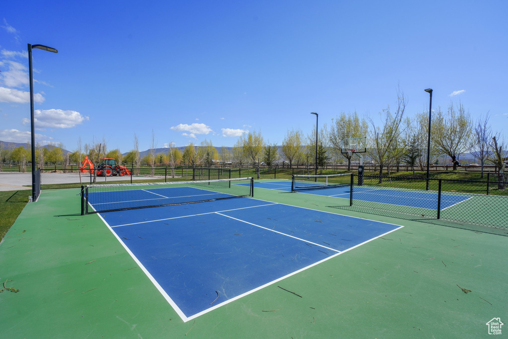 View of tennis court featuring playground community and fence