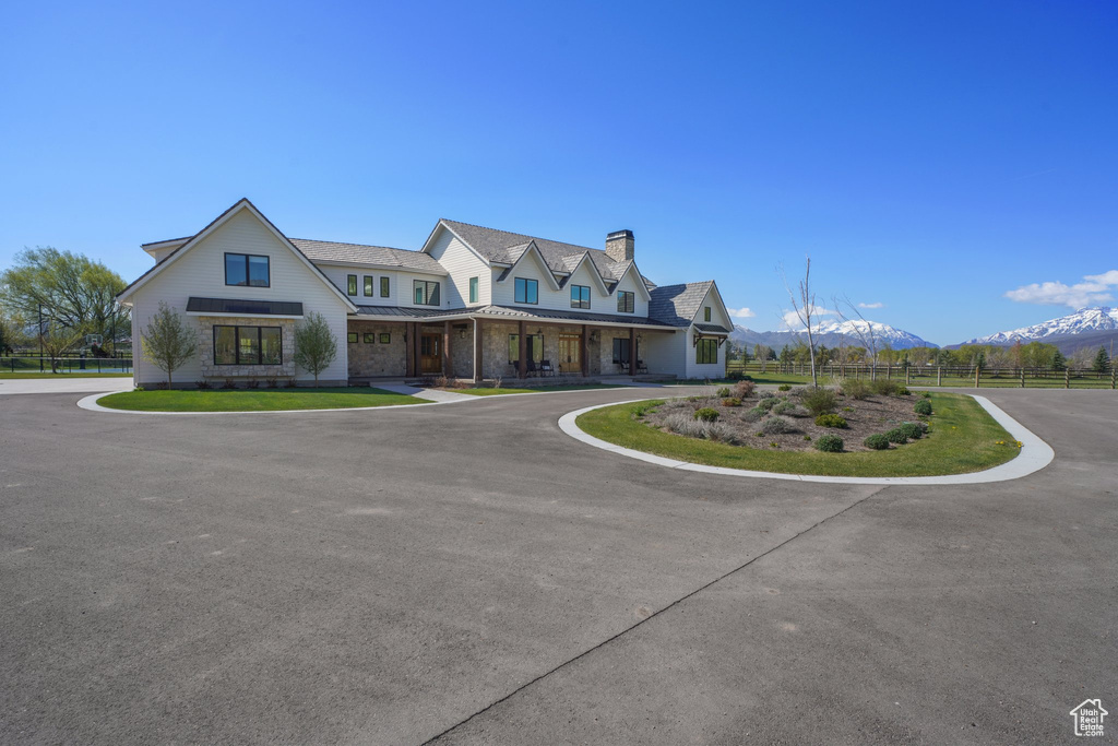 View of front facade with a porch, fence, a mountain view, a chimney, and a standing seam roof