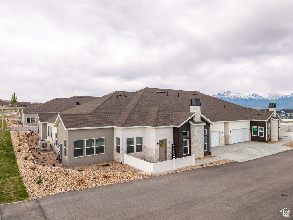 Ranch-style home featuring stone siding, stucco siding, driveway, a shingled roof, and an attached garage