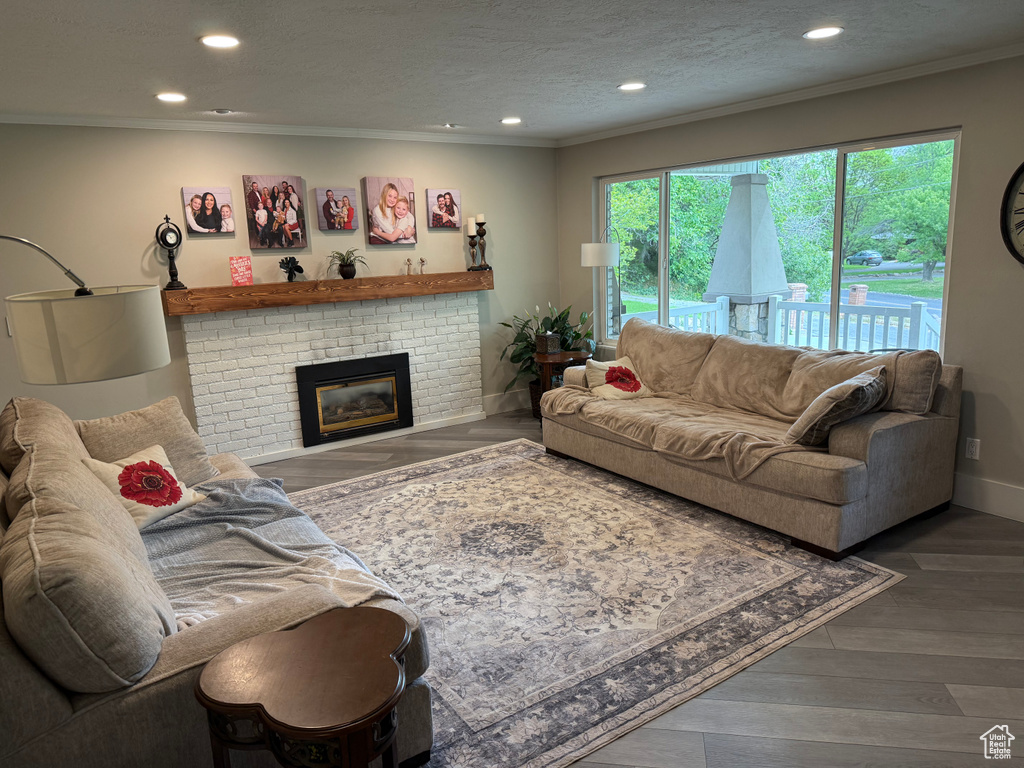 Living area featuring ornamental molding, recessed lighting, a brick fireplace, wood finished floors, and baseboards