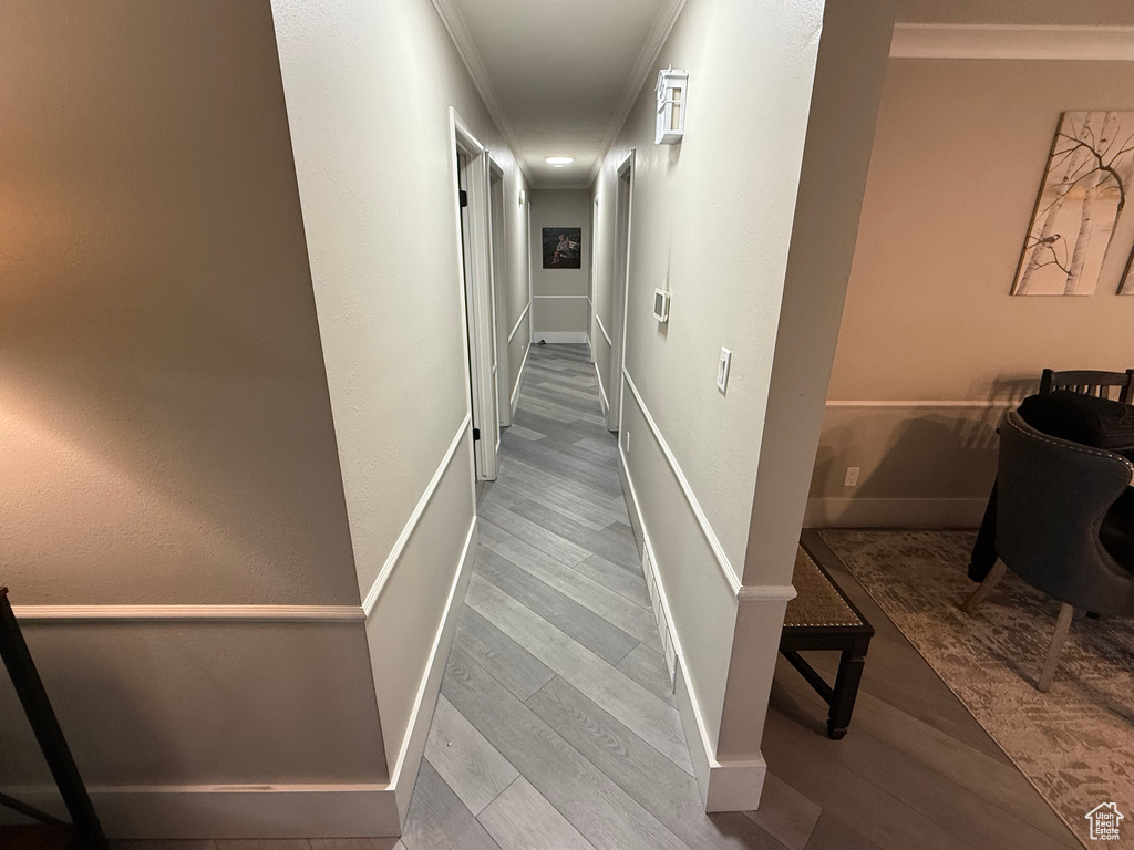 Stairs with wood finished floors, baseboards, and crown molding