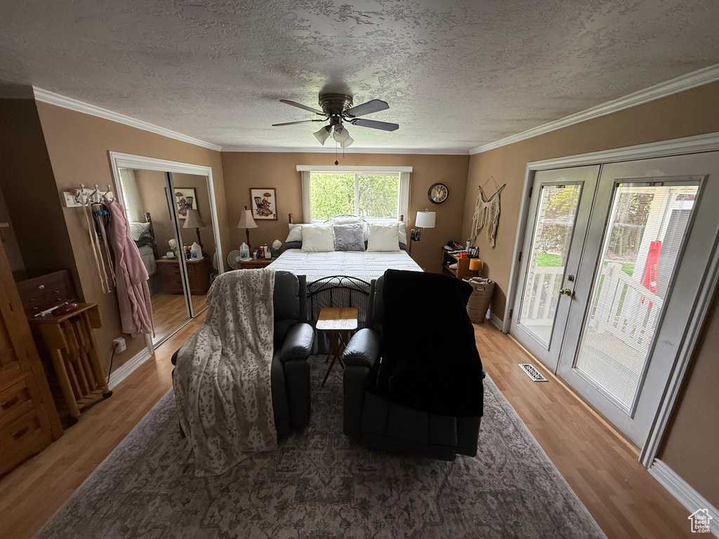 Bedroom with access to exterior, light wood-type flooring, a textured ceiling, ornamental molding, and a ceiling fan