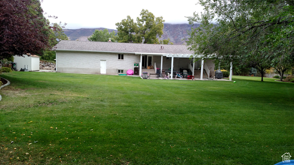 Rear view of property featuring a yard, a pergola, a mountain view, and a patio