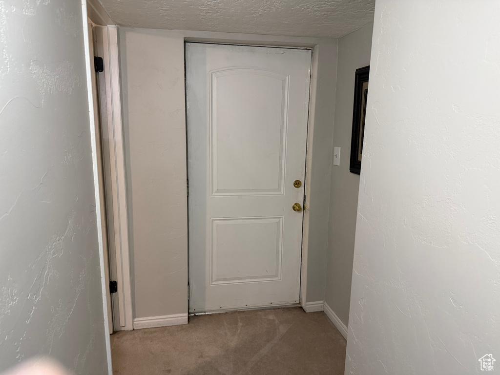 Corridor featuring light colored carpet and baseboards