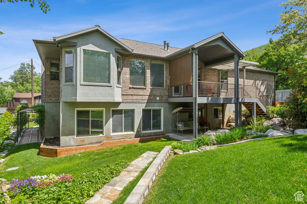 Rear view of property featuring a patio, a yard, stucco siding, stairway, and a deck