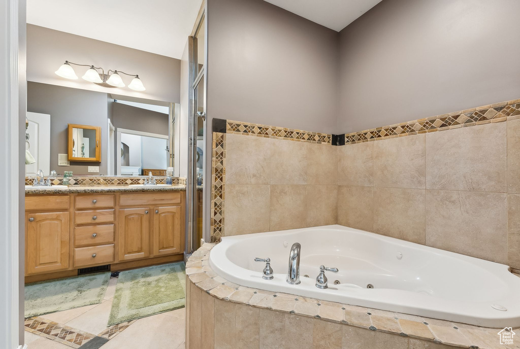 Full bath featuring a whirlpool tub, double vanity, a sink, and tile patterned floors