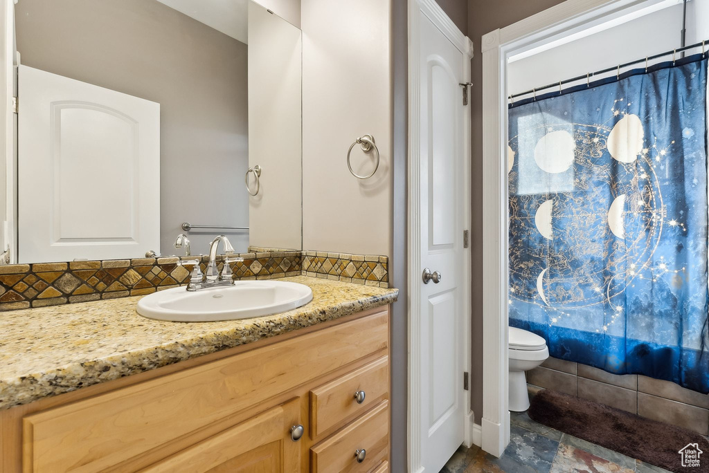 Full bathroom featuring decorative backsplash, shower / bath combo, vanity, and toilet
