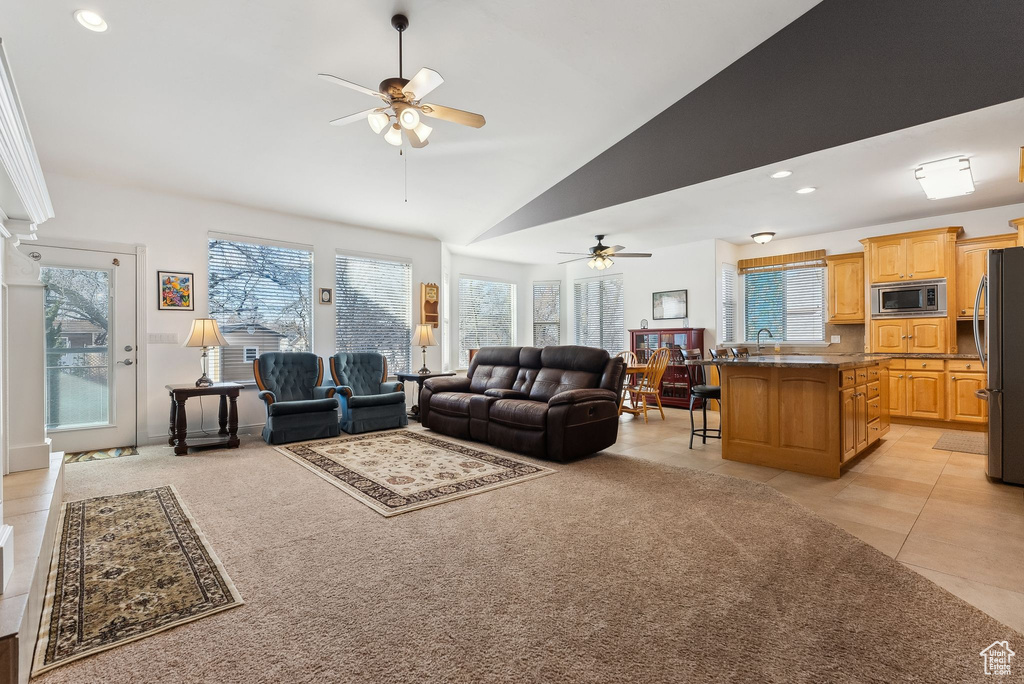 Living room with light tile patterned floors, high vaulted ceiling, light colored carpet, recessed lighting, and a ceiling fan