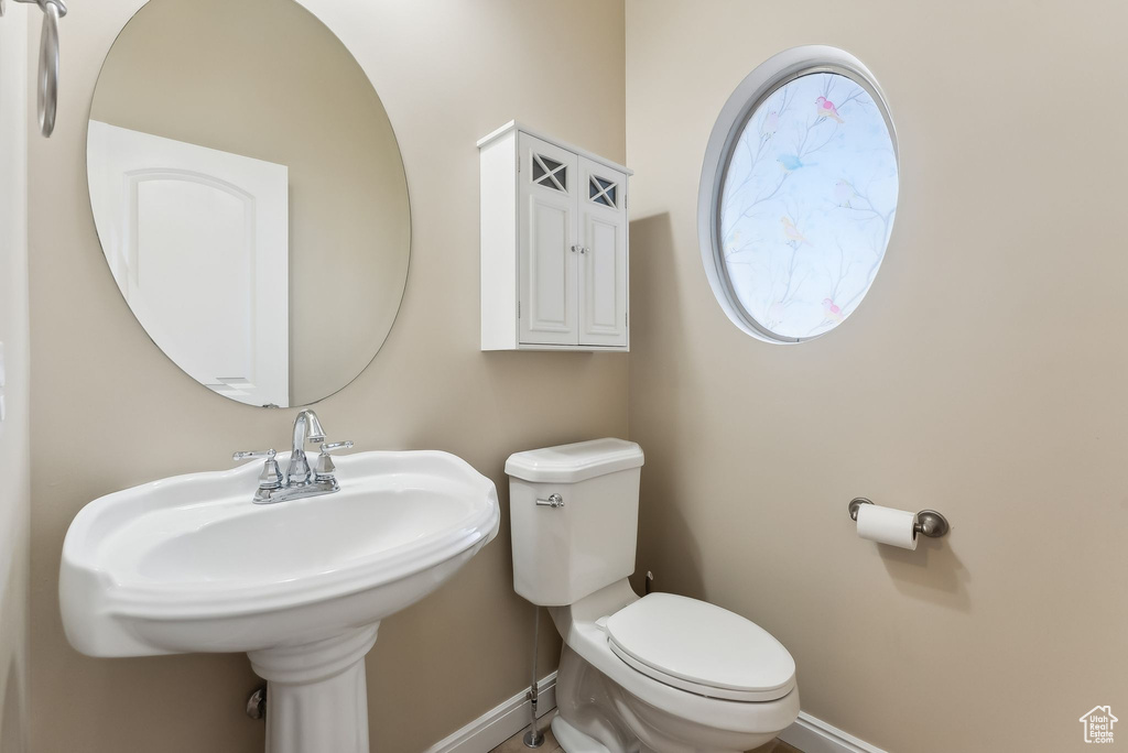 Half bathroom featuring baseboards, a sink, and toilet