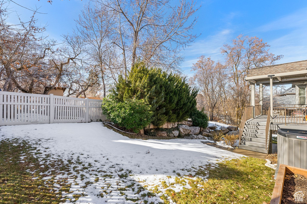 Yard covered in snow with fence and central air condition unit