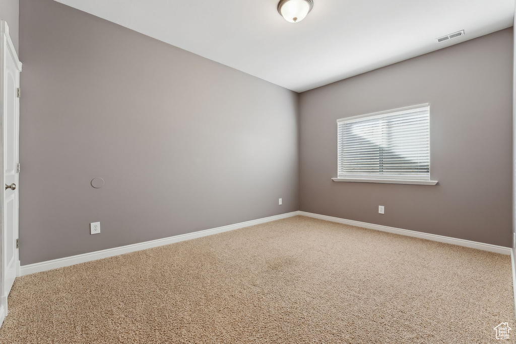 Spare room featuring carpet, visible vents, and baseboards