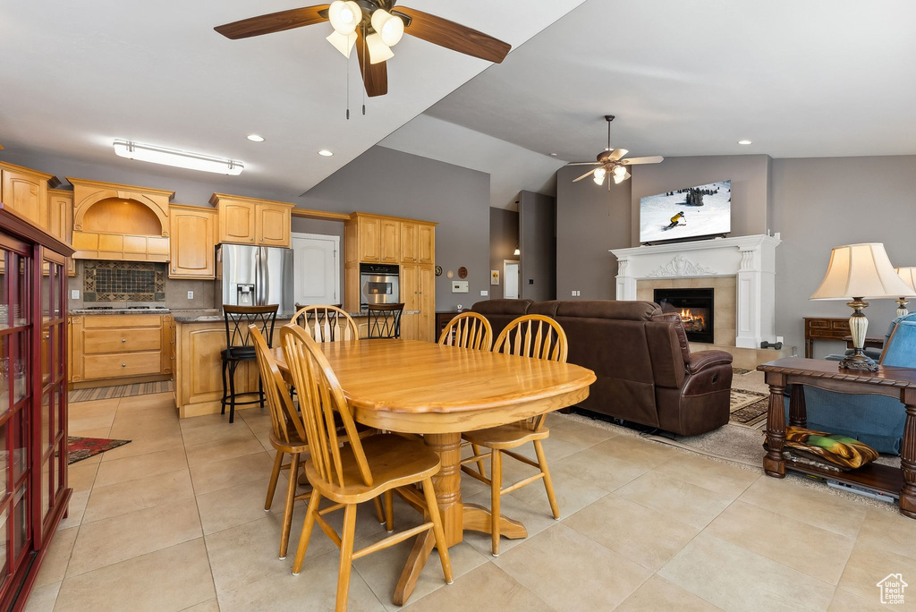 Dining room featuring light tile patterned floors, recessed lighting, a ceiling fan, vaulted ceiling, and a lit fireplace