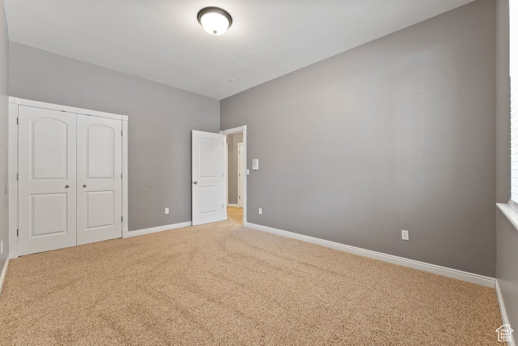 Unfurnished bedroom featuring carpet floors, baseboards, and a closet