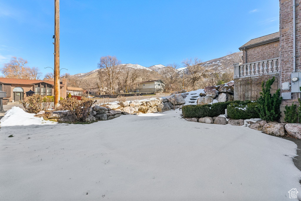Yard covered in snow featuring a mountain view
