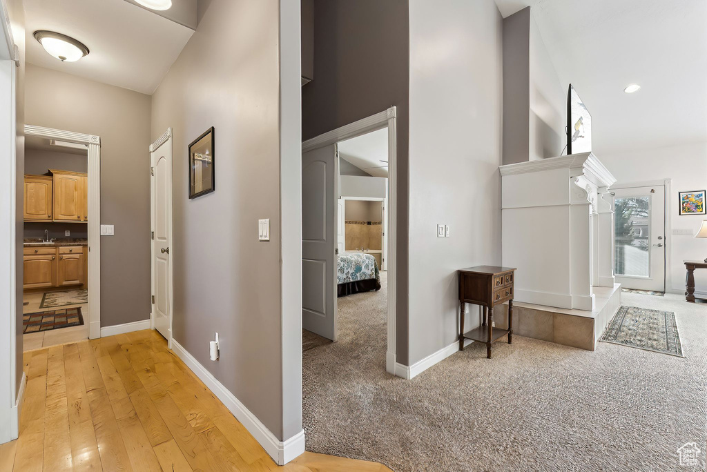 Hall with light wood-type flooring, baseboards, light colored carpet, and recessed lighting