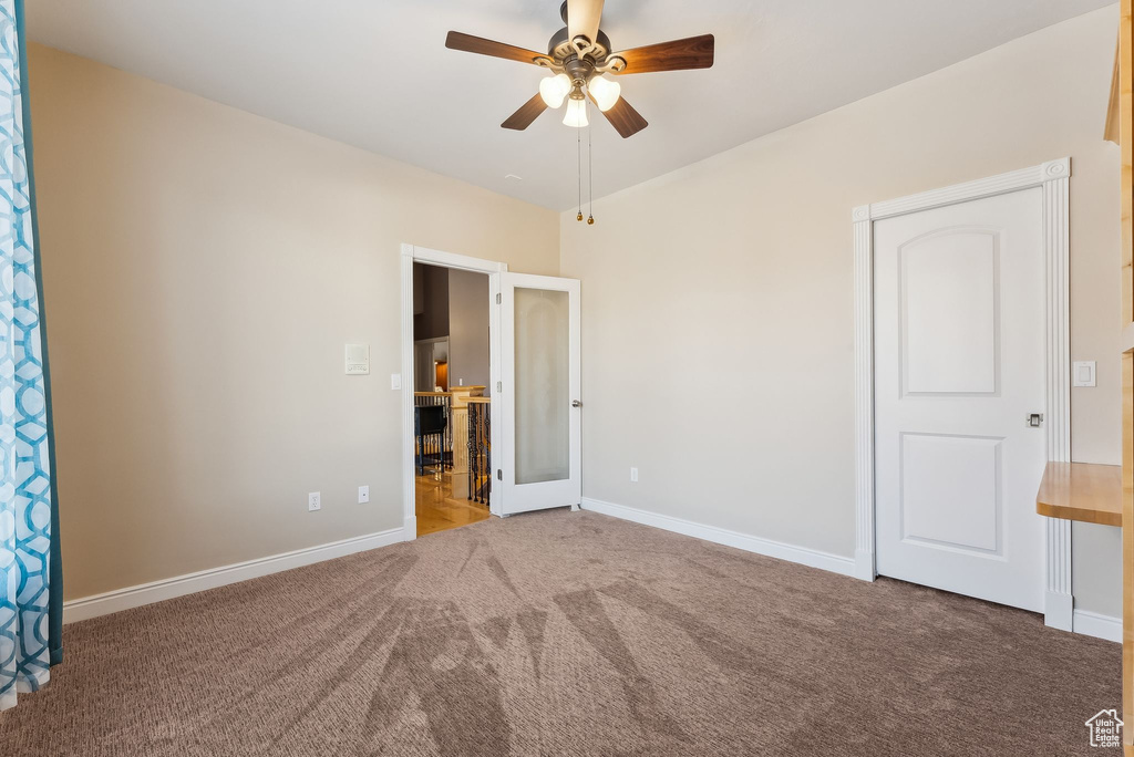 Unfurnished bedroom featuring carpet floors, baseboards, and a ceiling fan
