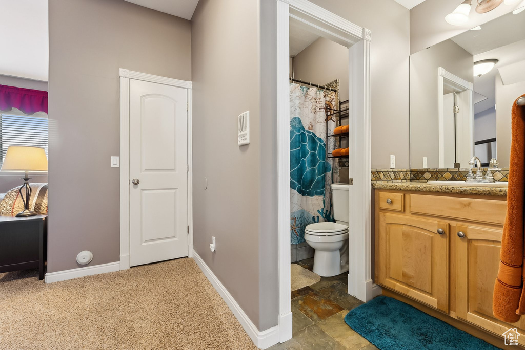Bathroom with a shower with shower curtain, baseboards, vanity, and toilet