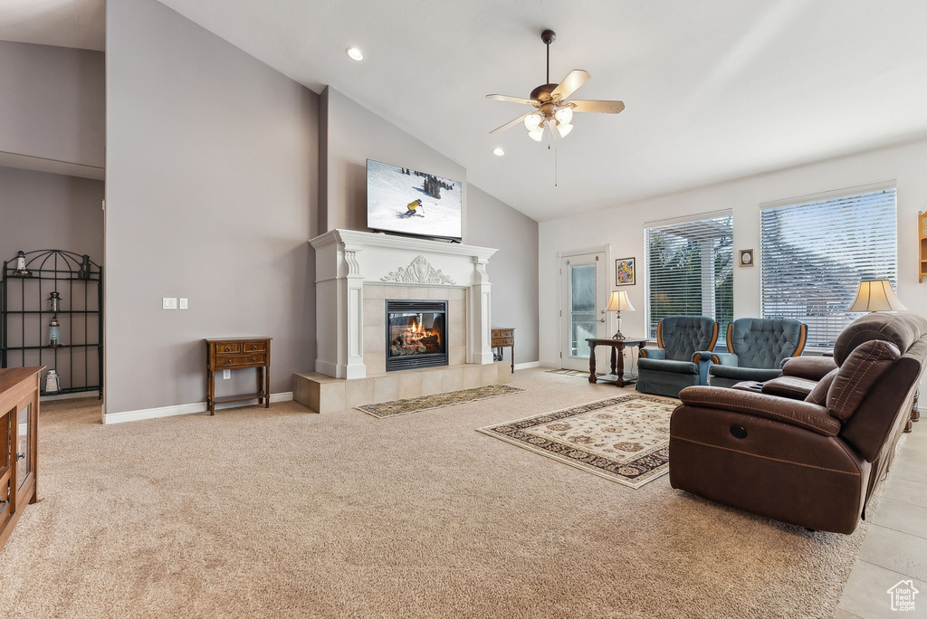 Living area with baseboards, high vaulted ceiling, light colored carpet, and a tile fireplace