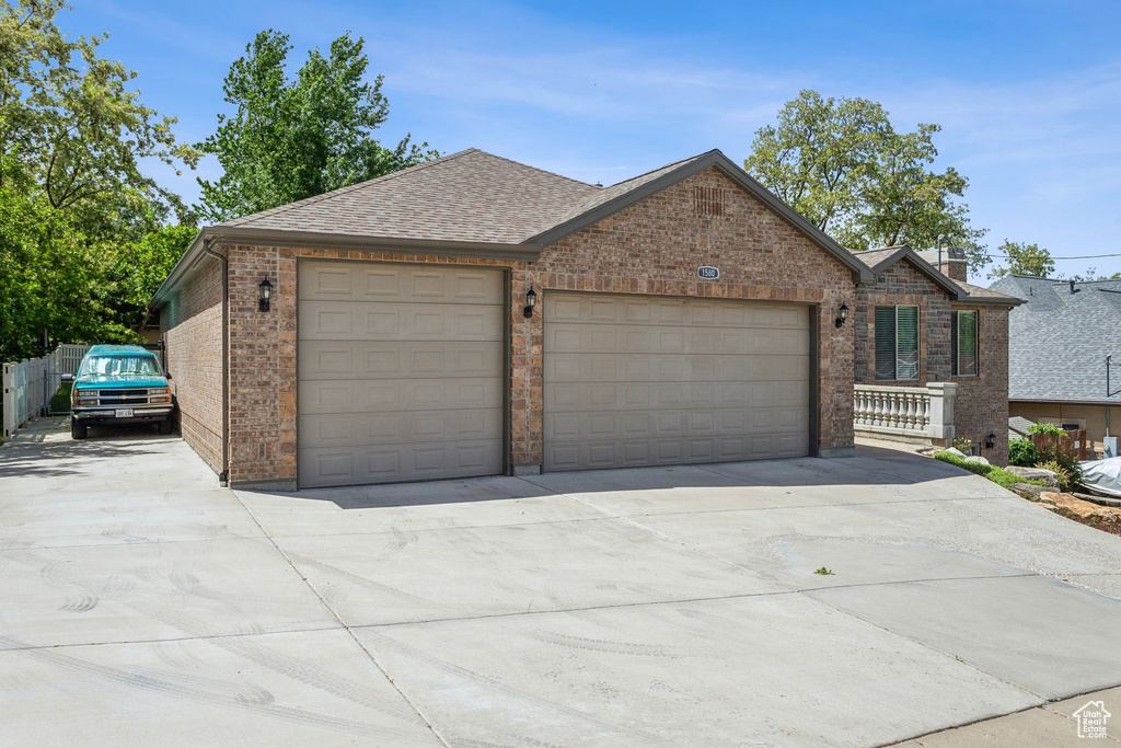 View of front of home featuring brick siding, driveway, a garage, and a shingled roof