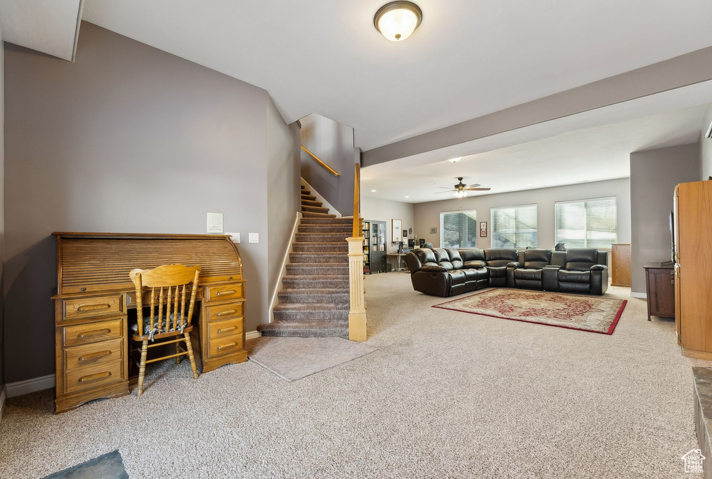 Living room with stairs, ceiling fan, carpet, and baseboards