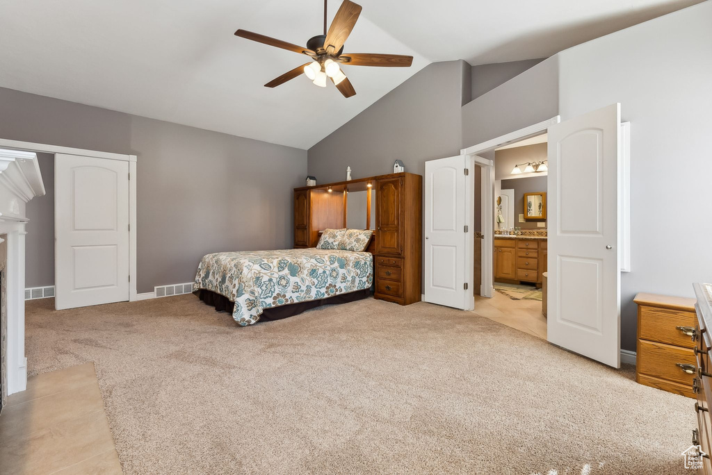 Bedroom with high vaulted ceiling, visible vents, connected bathroom, and light carpet
