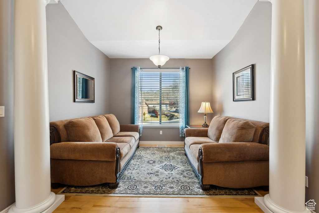 Living area with wood finished floors, decorative columns, and baseboards