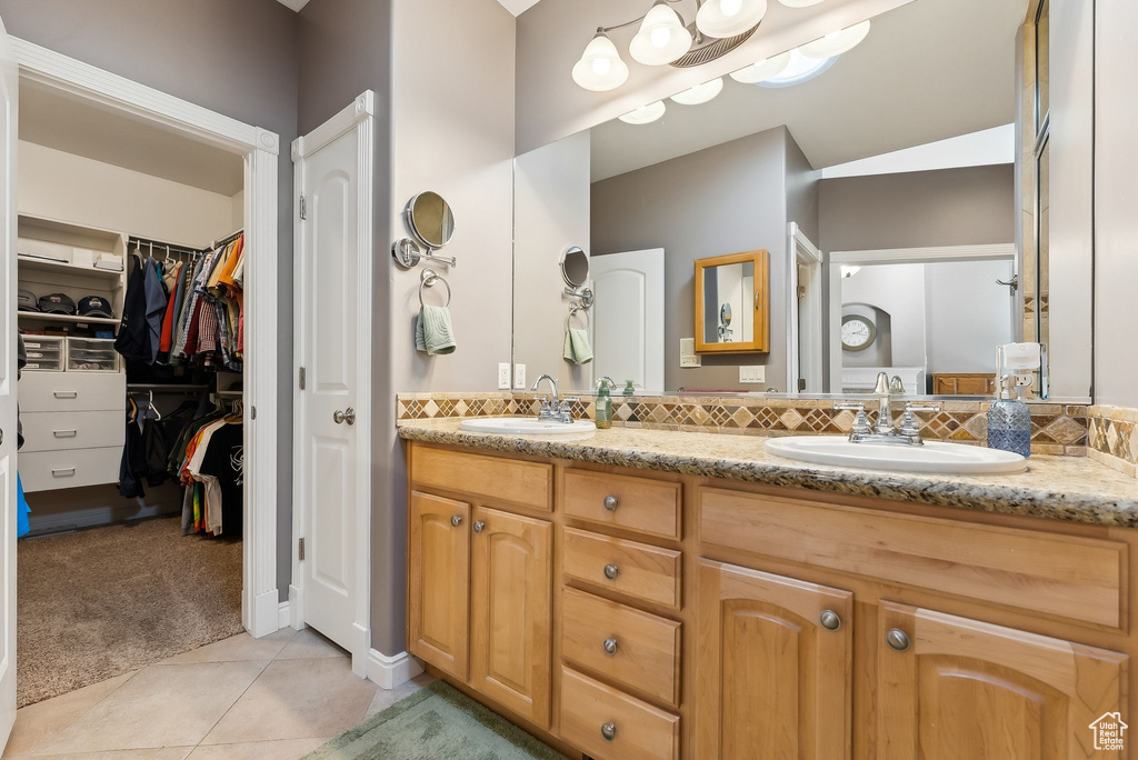 Bathroom with tile patterned floors, a sink, backsplash, and double vanity