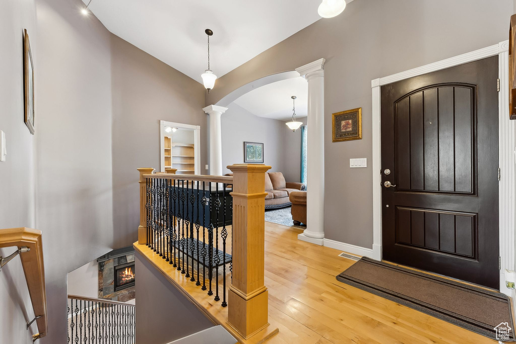 Foyer with arched walkways, visible vents, vaulted ceiling, wood finished floors, and ornate columns
