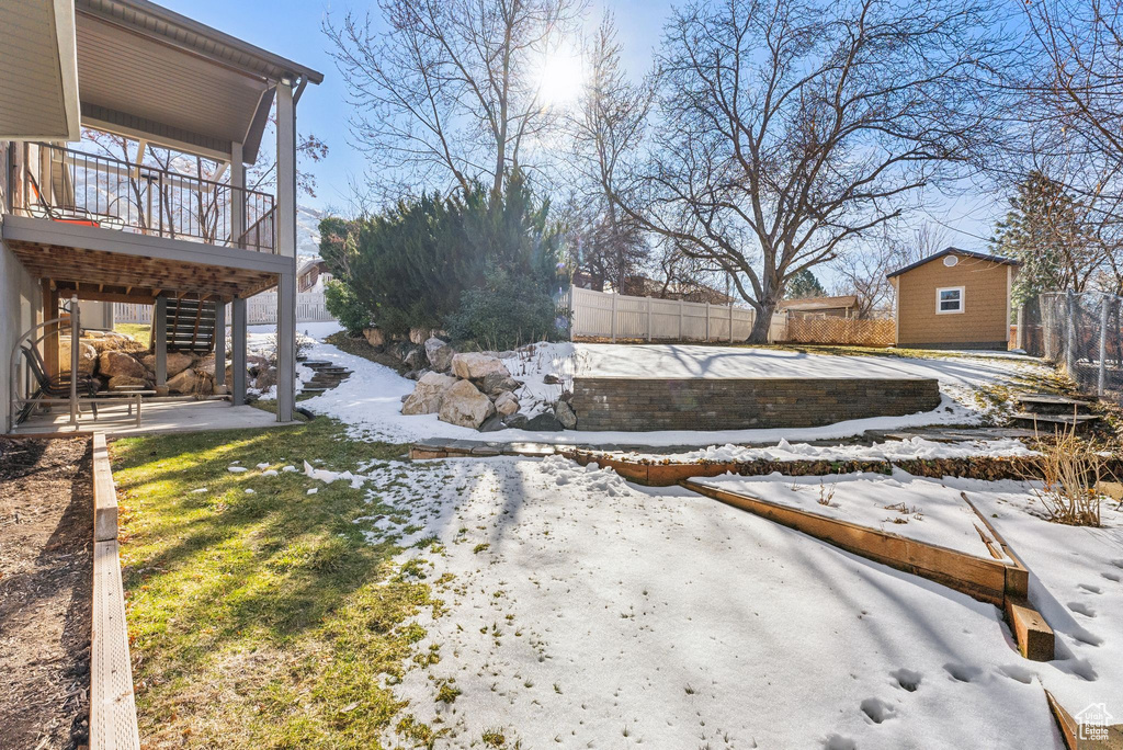 Yard layered in snow with an outdoor structure and fence