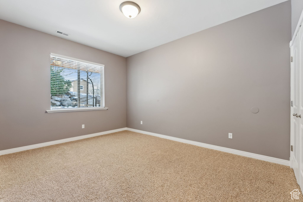 Spare room featuring carpet, visible vents, and baseboards