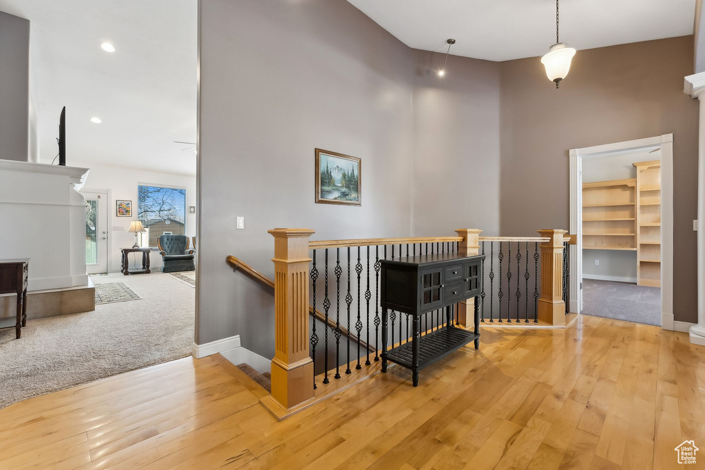 Hallway with baseboards, a towering ceiling, wood finished floors, an upstairs landing, and recessed lighting