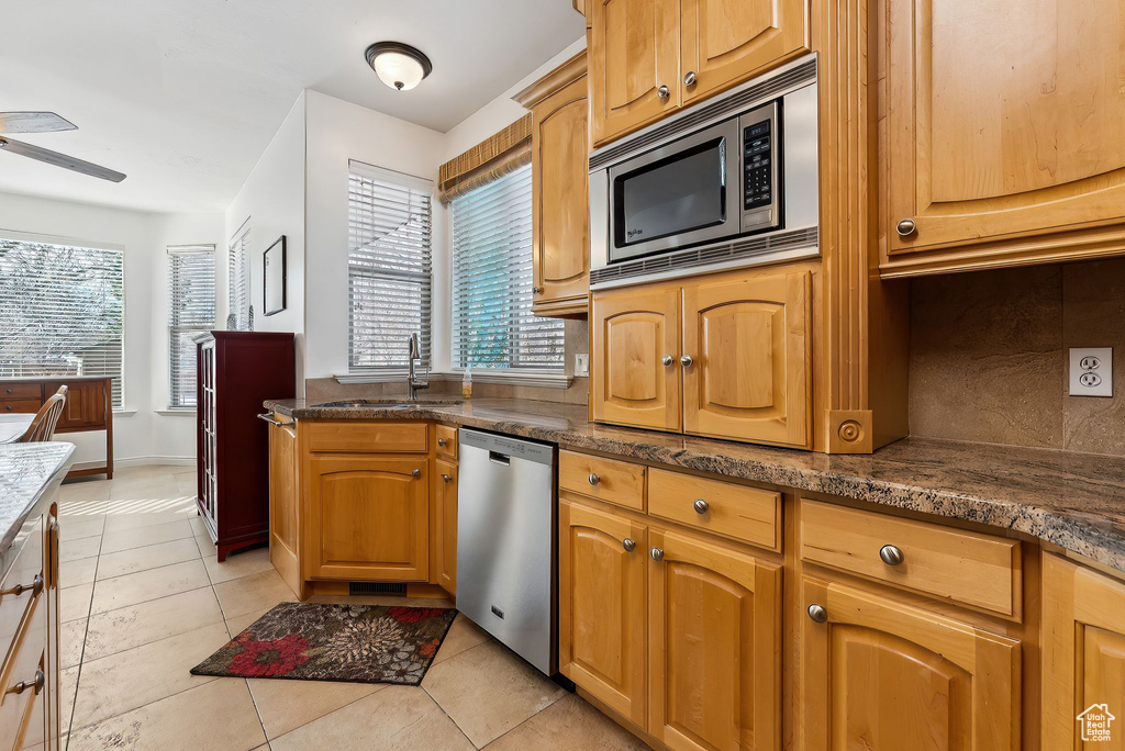 Kitchen featuring ceiling fan, a sink, stainless steel appliances, backsplash, and light tile patterned flooring