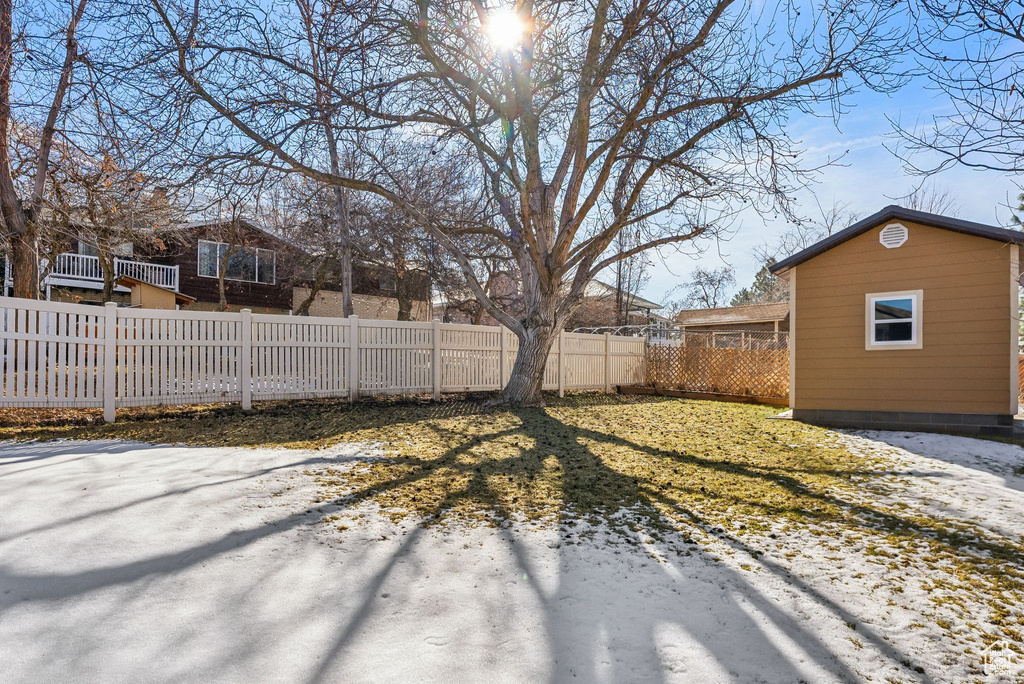 Yard layered in snow featuring a fenced backyard and an outbuilding
