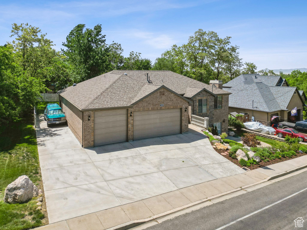 View of front of home with a garage, concrete driveway, brick siding, and a shingled roof