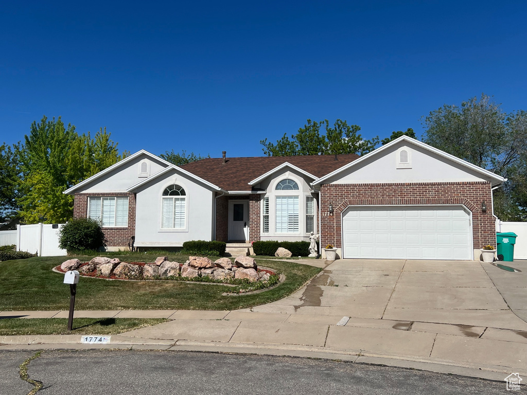 Ranch-style home featuring concrete driveway, a garage, brick siding, and stucco siding