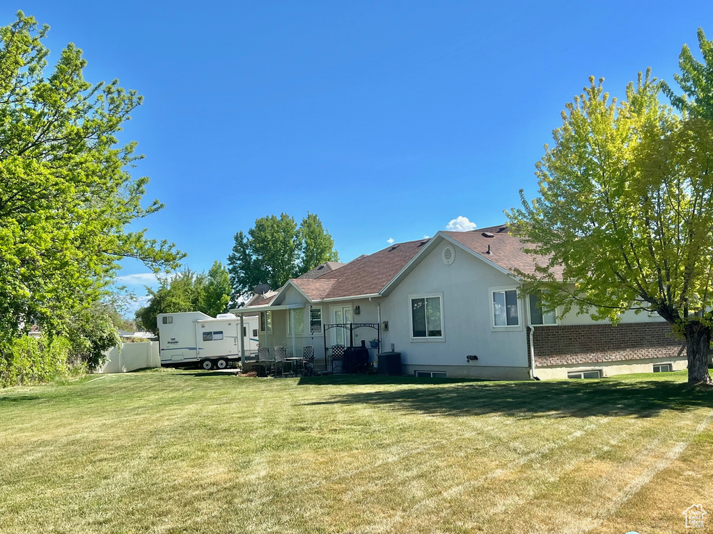 Rear view of property with a shingled roof, central air condition unit, and stucco siding